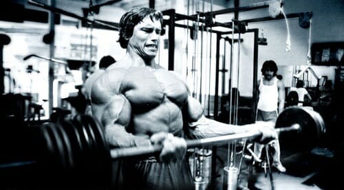 Black and white photo of Arnold Schwarzenegger at the gym
