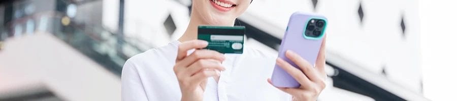 A woman holding her credit card and phone to buy the best probiotics for women