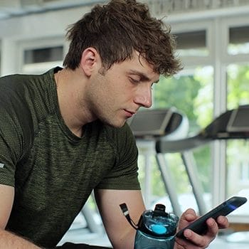 A guy in the gym browsing online to buy Onnit Shroom Tech Sport