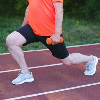 man performing lunges with a dumbbell