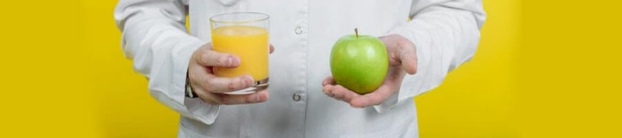 person holding juice and apple