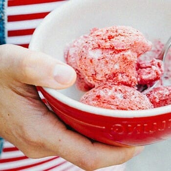 Hand holding a strawberry flavored sorbet in a bowl