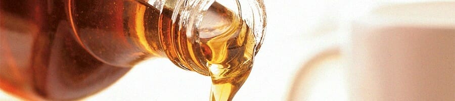 Close up shot of a maple syrup being poured out of a bottle