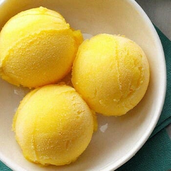 Three scoop of mango sorbet in a bowl