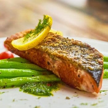 close up image of a cooked salmon with beans and lemon slice