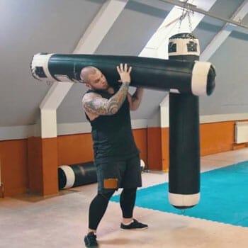 man lifting a heavy bag inside a gym