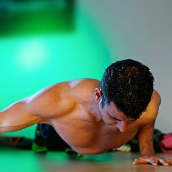 shirtless man in a single hand push up position