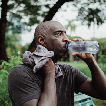 black man wiping his sweat while chugging water