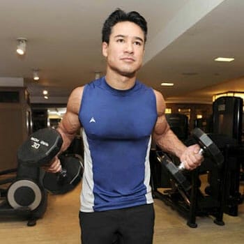 mario lopez holding dumbbells on both hands inside a gym