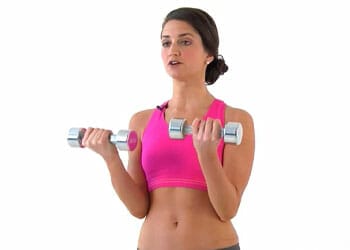 woman in a pink top working out with dumbbells