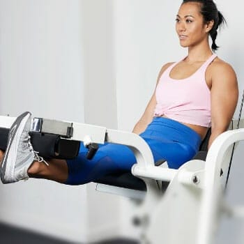 woman using a leg extension machine inside a gym