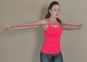 woman wearing a pink top using a resistance band