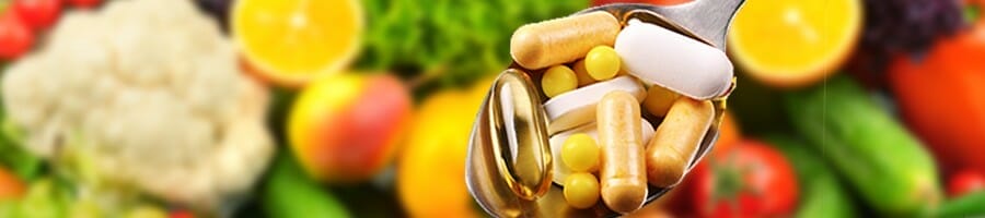 A spoon of supplements in a background of blurred foods