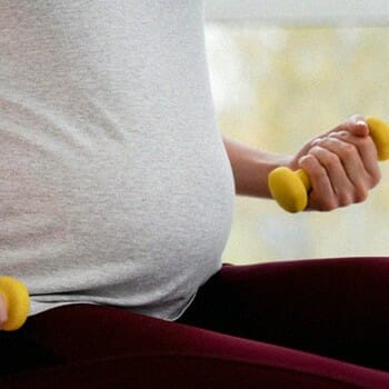 Pregnant person lifting dumb bells