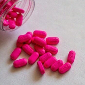 Pink supplements compressed on a surface