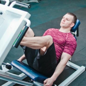 man using a leg press machine inside a gym