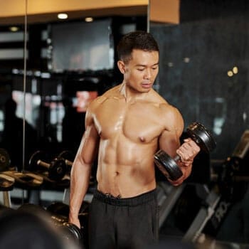 shirtless asian man working out with a dumbbell on one arm
