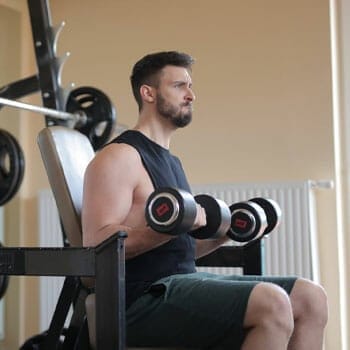 man using dumbbell curls in a gym