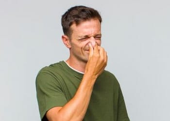 man in a green shirt blocking his nose