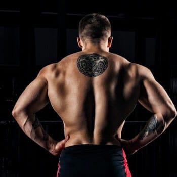 shirtless man with tattoos flexing his back muscles