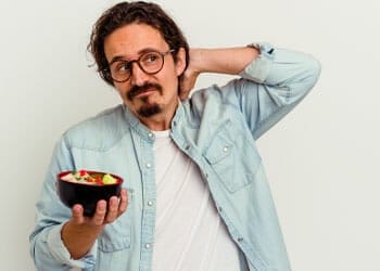 man contemplating while holding his neck and a bowl of food