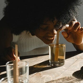 woman smelling and mixing an alcohol drink