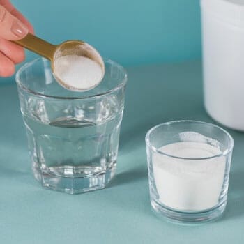 pouring scooped collagen in a glass of water