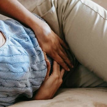 woman laying down holding her stomach in pain
