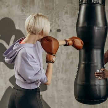 woman wearing a boxing gloves while punching a heavy bag