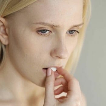 close up image of woman putting a pill inside her mouth