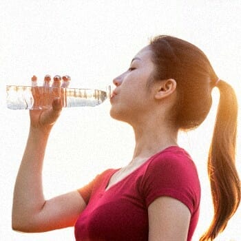 A woman wearing a red shirt drinking water