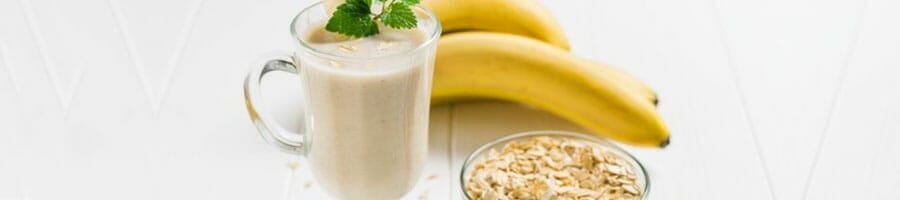 jar filled with banana smoothie and a bowl of oats on the side