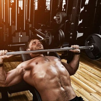 shirtless man using a barbell in a bench