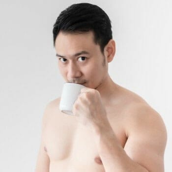 shirtless man sipping coffee