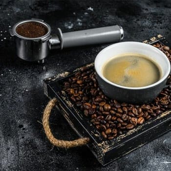coffee cup on coffee beans and a scoop of coffee ground on the side