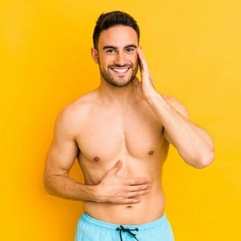 shirtless man holding his abs smiling