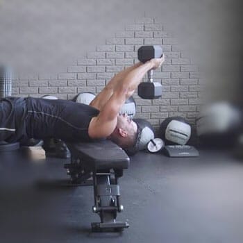 man doing dumbbell pullovers in a gym
