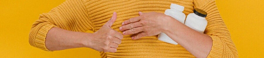 Woman holding supplement containers while giving a thumbs up