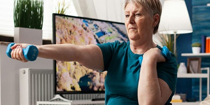 Woman watching aeorobic workout using tablet sitting swiss ball