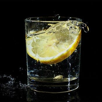 water splashing from a drinking glass with lemon