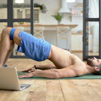 shirtless man in a bridge position on a yoga mat