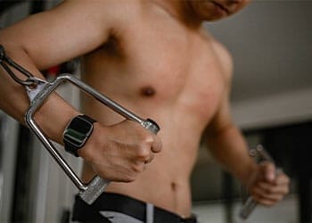 close image of shirtless man's hand gripping a cable machine
