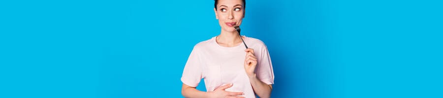 woman with a fork in her mouth and holding her stomach