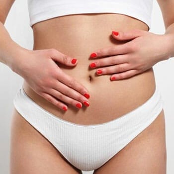 woman in white underwear placing both of her hands on her bare stomach