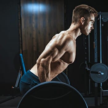 A healthy guy lifting a barbell and doing bent over barbell rows