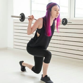 A woman doing a barbell split squats