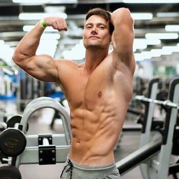 Shirtless Connor Murphy flexing his muscles in a gym