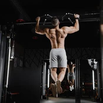 shirtless man in the gym doing pull ups