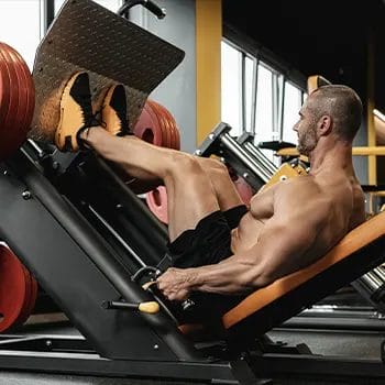 shirtless man using a leg press machine