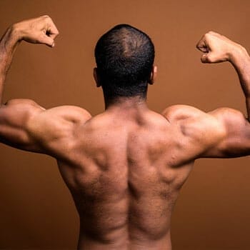 shirtless man showing his back while flexing arms